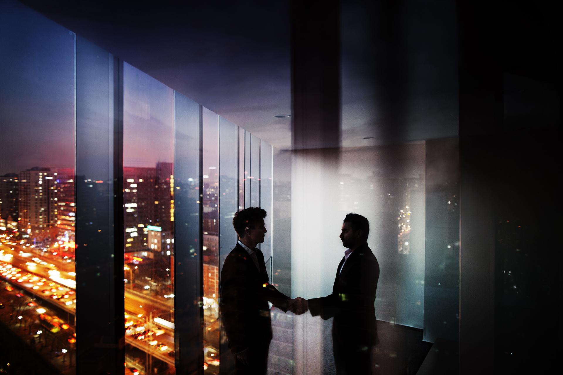 Two men shaking hands in the dark